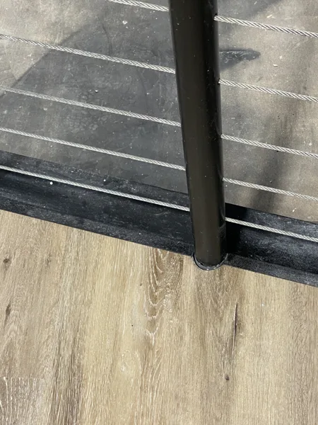 The plank landing meets the stair edge beside the railing post. The fitted edges keep this change in level visually connected.