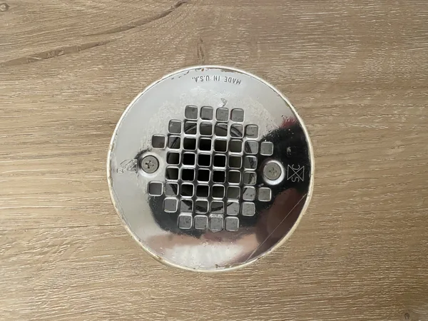 Carefully shaped cuts follow the circular opening, keeping the finished flooring edge close to the drain cover.