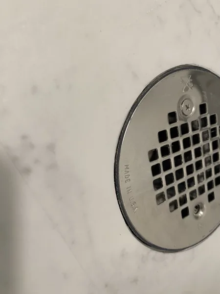 Carefully shaped cuts follow the circular opening, keeping the finished flooring edge close to the drain cover.