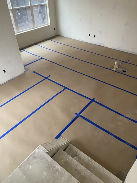 Protective paper and taped seams cover the floor during ongoing construction.
