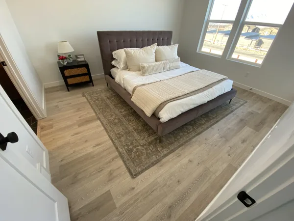 Laminate flooring around the bedroom rug and furniture.