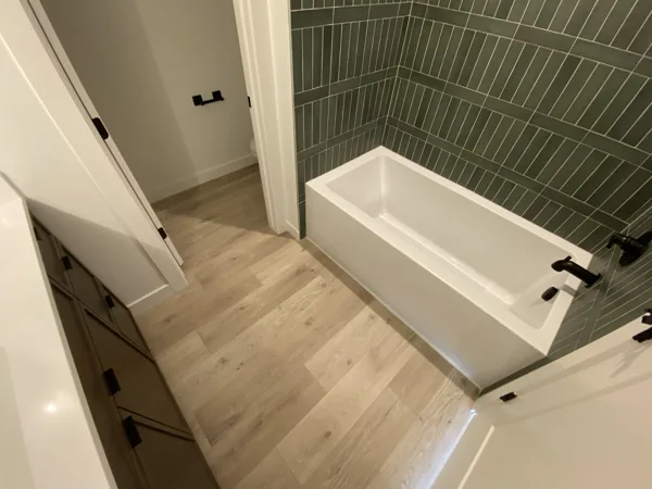 The plank floor and wall finish beside the bathtub.