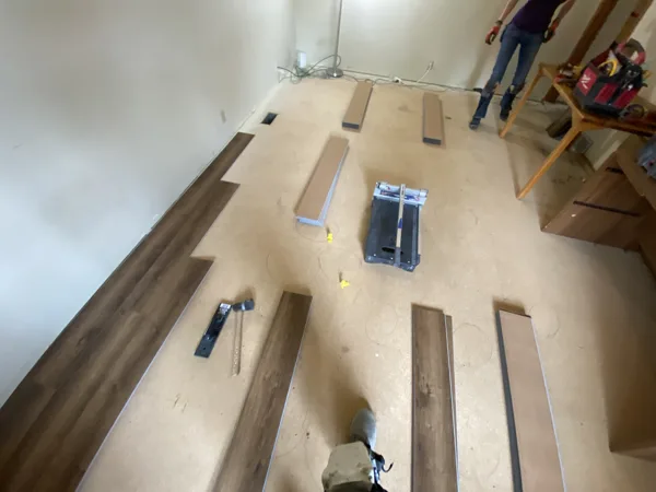 Plank flooring and installation work in the office around the desks and shelving.