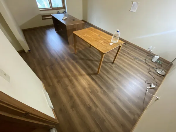 Plank flooring and installation work in the office around the desks and shelving.