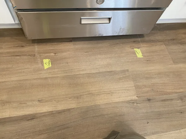 Marked plank areas near the appliance before the repair.